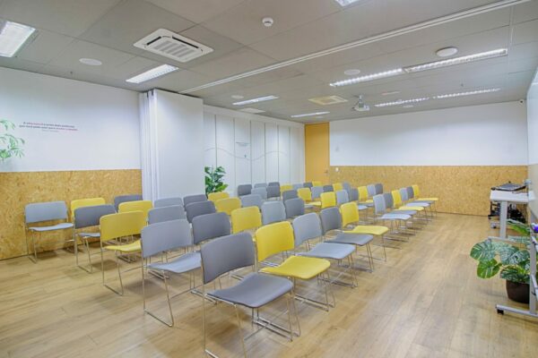 Auditório amplo, com 50 cadeiras coloridas, projetor, lousa e mesa de som