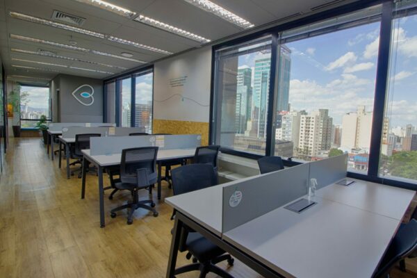 Foto das mesas de escritório do espaço compartilhado com vista para os prédios do bairro Paraíso